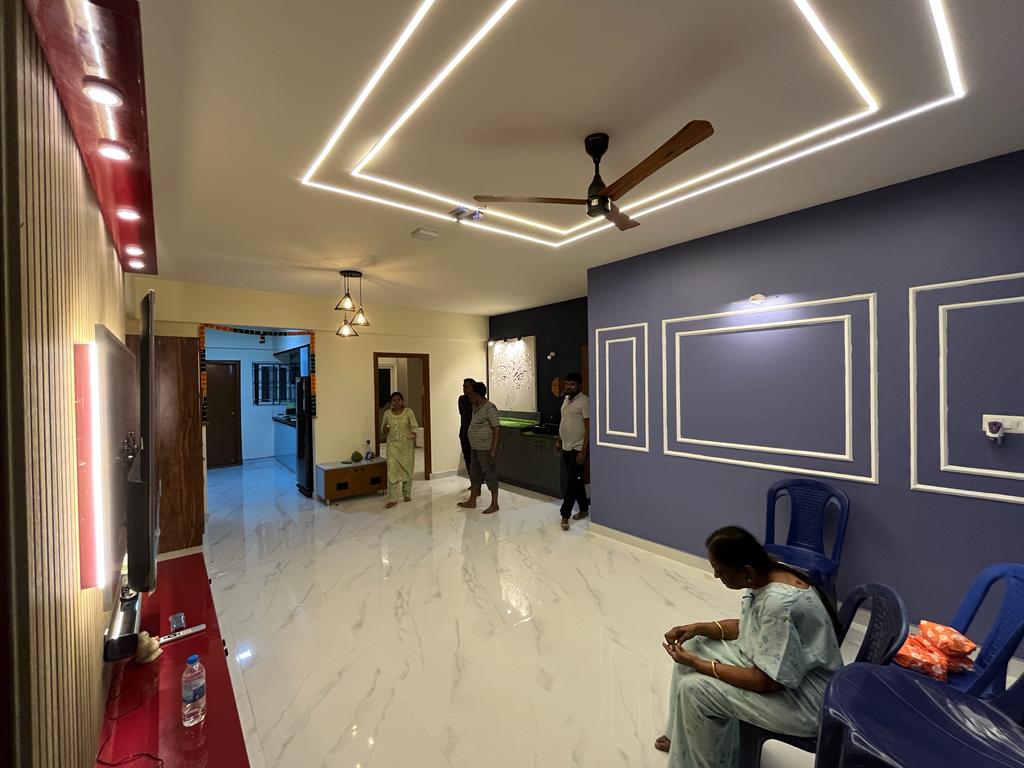 Rohan's Flat, Bangalore — Open living area with wall mouldings, glossy red TV unit and linear cove lighting
